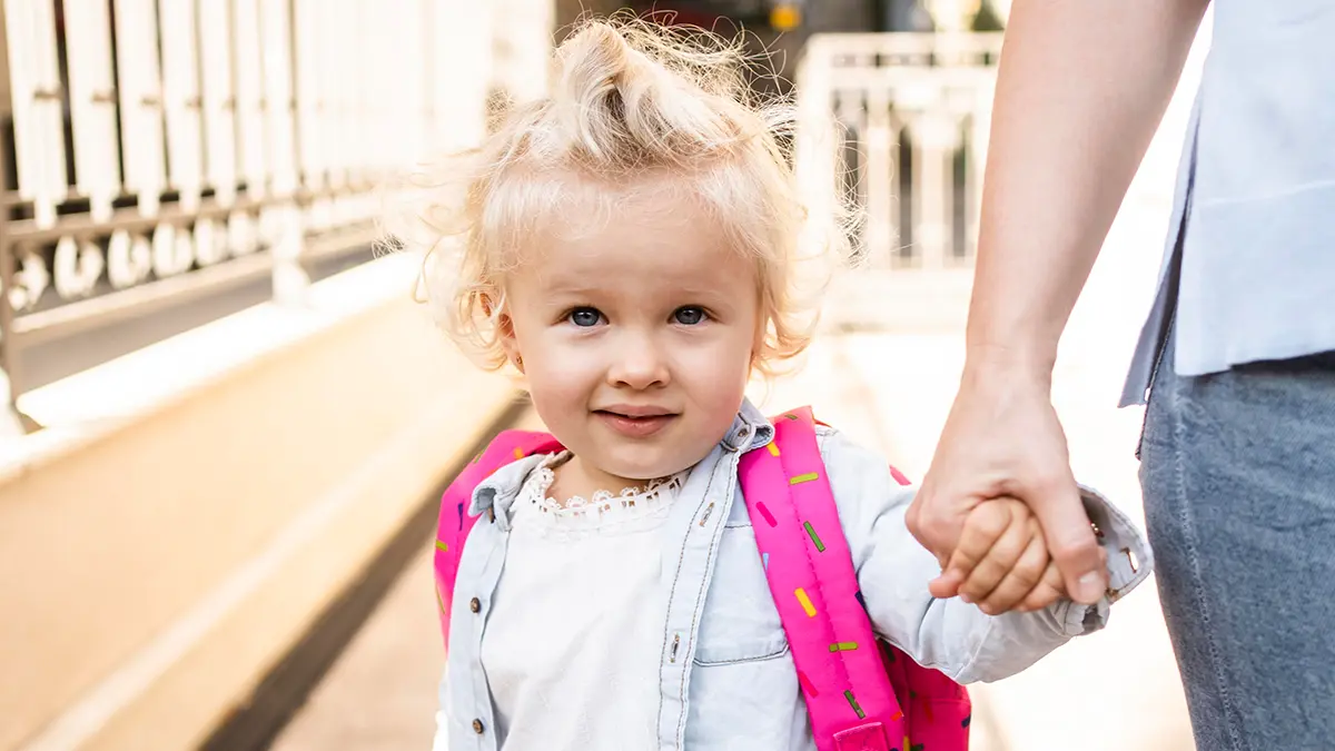 Toddler with labeled backpack during calm drop-off—STEAM childcare routines in Skyway