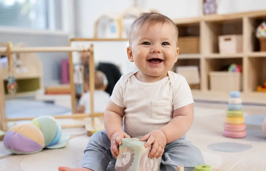 Infant smiling during childcare at Little STEAMers Academy